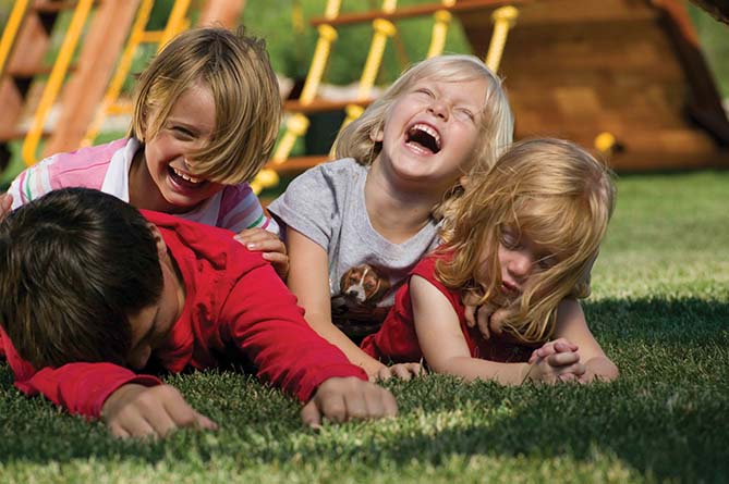 Дети смеются в траве возле Rainbow